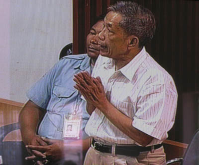 Posture de Duch quand il authentifie des documents. C'est notamment ainsi qu'il reconnaît la détention à S21 de Norng Chanphal. (Anne-Laure Porée)